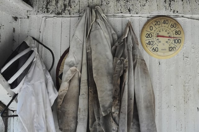 Beekeeping suits hang next to an outdoor thermometer Tuesday, June 24, 2025, at Honeyrun Farm in Williamsport, Ohio. (AP Photo/Joshua A. Bickel)