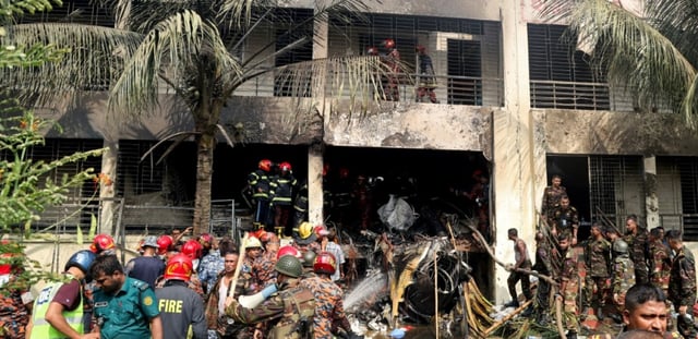 Des pompiers et des membres de la sécurité sur le site du crash d'un avion de l'armée de l'air sur une école à Dacca, le 21 juillet 2025 au Bangladesh