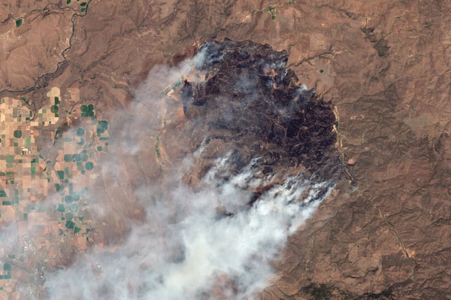 MADRAS, OR - 15 JULY 2025: A satellite view captures dense smoke plumes driven by extreme heat, gusty winds, and rugged terrain. The Cram Fire in Oregon is currently the state&#39;s largest active wildfire,