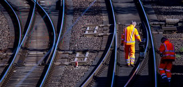 Bauarbeiter vermessen eine Schiene auf einer Bahnstrecke