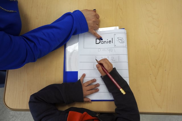 FILE - Easterseals Head Start program teaching assistant Tania Ortiz helps a student practice writing his name, Jan. 29, 2025, in Miami. (AP Photo/Rebecca Blackwell, File)
