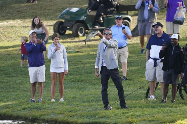 Sep 24, 2022; Charlotte, North Carolina, USA; Paul Azinger holds up a fish at the lake near the 14th hole during the foursomes match play of the Presidents Cup golf tournament at Quail Hollow Club. Mandatory Credit: Peter Casey-USA TODAY Sports/File Photo