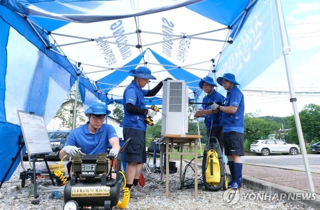 This photo, taken July 21, 2025, and provided by Samsung Electronics Co., shows the company's employees inspecting and repairing water-damaged home appliances in a flood-hit area. (PHOTO NOT FOR SALE) (Yonhap) 