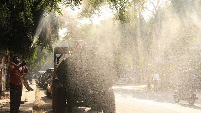 Representational image | A worker sprays water to curb air pollution | ANI