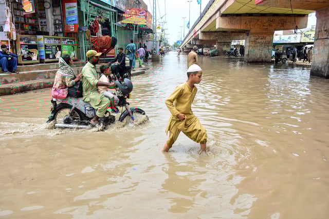 Des personnes pataugent dans une rue inondée après de fortes pluies de mousson à Hyderabad, dans la province de Sindh au Pakistan, le 20 juillet 2025.