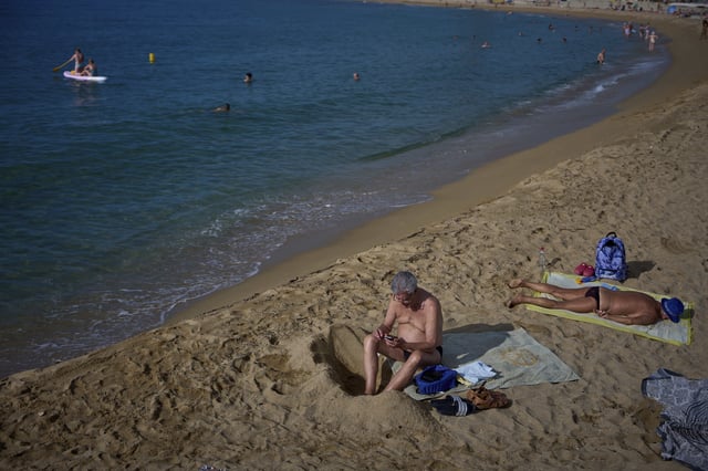 Sunbathers relax on a beach in Barcelona, Spain, Tuesday, July 22, 2025. (AP Photo/Emilio Morenatti)