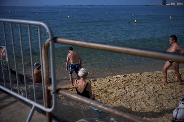 Sunbathers relax on a beach in Barcelona, Spain, Tuesday, July 22, 2025. (AP Photo/Emilio Morenatti)