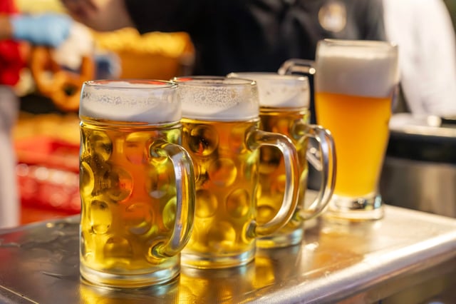 Deutschland, München, 20. Juli 2025, Biertrinken bei Kerzenschein um 5 Uhr, traditioneller Kocherlball am Chinesischen Turm, Englischer Garten, 3 halbe Helle und ein Weißbier am Ausschank, Besucher sitzen schon teilweise ab 4 Uhr früh im Biergarten, trinken ein Bier, essen eine Brotzeit, tragen Tracht, Tradition entstand im 19. Jahrhundert, als Hauspersonal, Dienstboten und KöchInnen in den frühen Morgenstunden vor Dienstbeginn gefeiert und getanzt haben, Tradition wurde ab 1989 wiederbelebt, traditionell am 3. Sonntag im Juli, feiern, Tradition, traditionell, Bayern, typisch bayerisch, Frühaufsteher, Oberbayern,