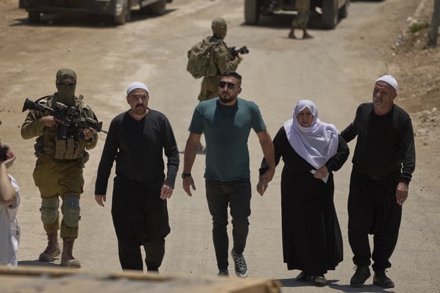 Syrian Druze people cross back into Syria as they walk at the Israeli-Syrian border, in the Israeli-controlled Golan Heights town of Majdal Shams, Thursday, July 17, 2025.