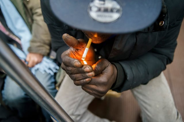 A man lights a cigarette on a CTA Blue Line train after leaving the Pulaski station toward the Loop, March 15, 2022, in Chicago. (Armando L. Sanchez/Chicago Tribune)