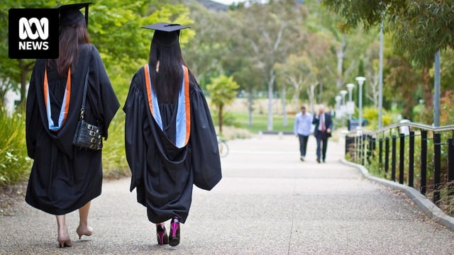 Two women wearing University graduation gowns and mortar boards.