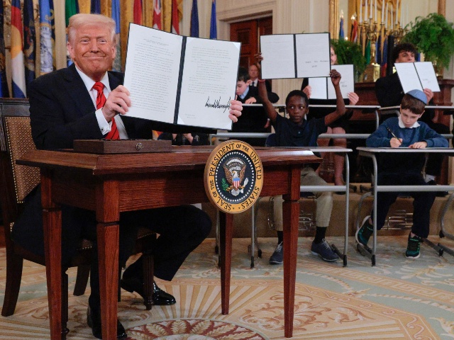 WASHINGTON, DC - MARCH 20: (EDITOR'S NOTE: Alternate crop) Joined by children seated at school desks, U.S. President Donald Trump holds up the signed executive order to reduce the size and scope of the Education Department during a ceremony in the East Room of the White House on March 20, 2025 in Washington, DC. The order instructs Education Secretary Linda McMahon, former head of the Small Business Administration and co-founder of the World Wrestling Entertainment, to shrink the $100 billion department, which cannot be dissolved without Congressional approval. (Chip Somodevilla/Getty)