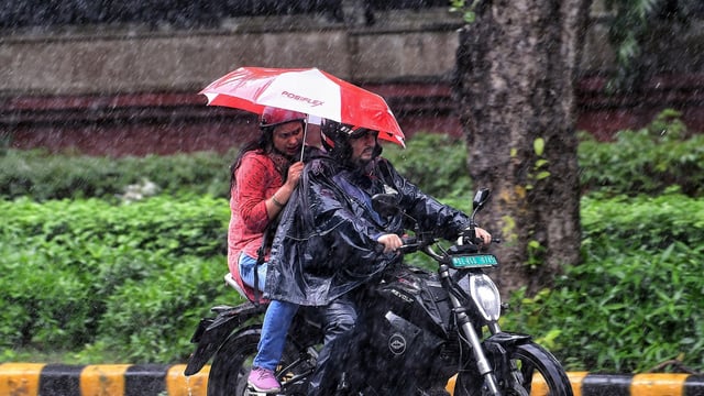  Commuters cover themselves amid heavy rainfall, in New Delhi
