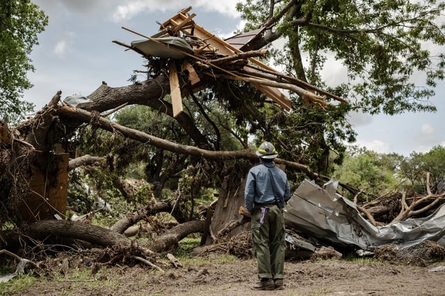 A member of a fire crew assess how to remove debris from a tree during continued search and recovery operations on the bank of the Guadalupe River in Ingram, Texas, on July 12.