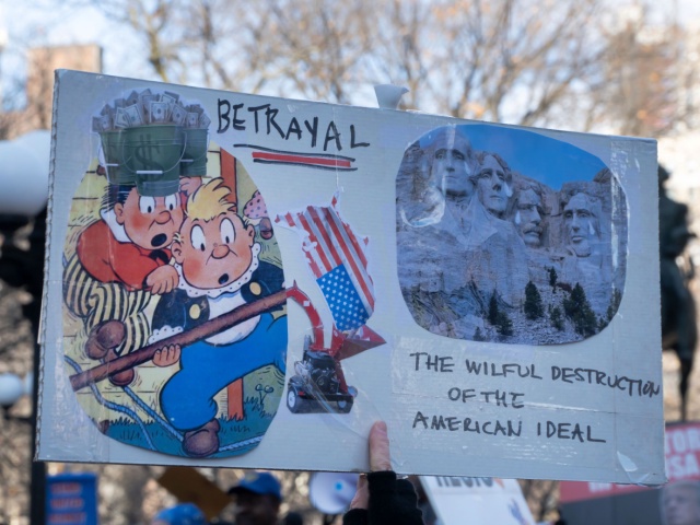 In a large crowd in Union Square on Presidents Day 2025, a homemade collage proclaims "betrayal" and shows tears running down the four Presidents' faces carved into Mount Rushmore. In this close up view, on one side of the collage, two cartoon-like characters appear very surprised. One wears a hat made of pails overflowing with cash; both watch an upside down American flag in tatters. On the other side is the teary Mount Rushmore image. Below that, text reads "The willful destruction of the American Ideal." . (Photo by: John Senter/UCG/Universal Images Group via Getty Images)