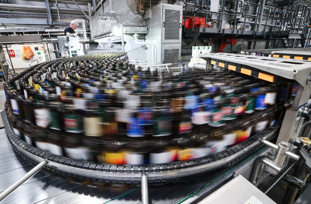 Flaschen laufen durch eine Anlage in einer Brauerei (Symbolbild).