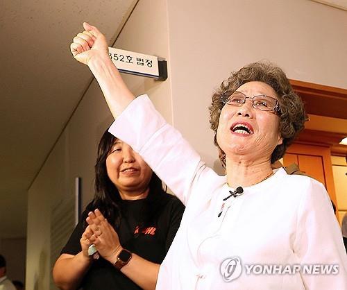 Choi Mal-ja raises her fist after attending a retrial of her attack on an attempted rapist 61 years ago at the Busan District Court in the southeastern port city of Busan on July 23, 2025. (Yonhap)