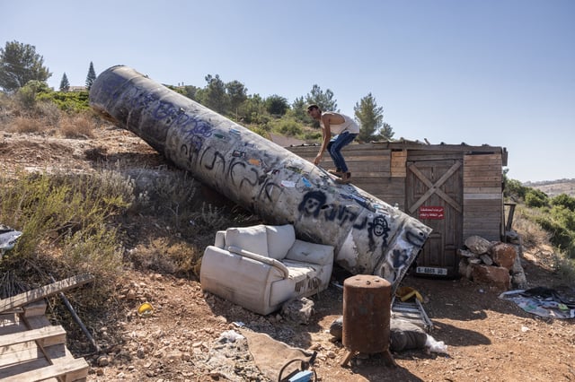 A man climbs on the remains of an Iranian missile that fell at the settlement of Neria near Ramallah, in the occupied West Bank, on 29 June 2025, in the aftermath of the 12-day war between Israel and Iran. The 12-day war erupted on June 13, when Israel launched a bombing campaign in Iran that killed top military commanders and scientists linked to its nuclear programme.