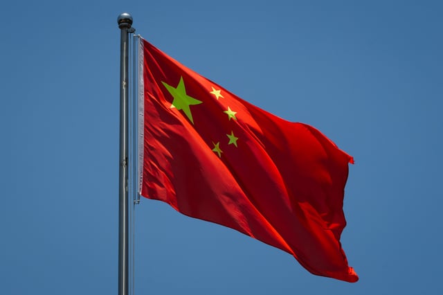 The national flag of the People&#39;s Republic of China flutters in the wind against a clear blue sky in front of the Chongqing People&#39;s Auditorium on June 16, 2025, in Chongqing, China.