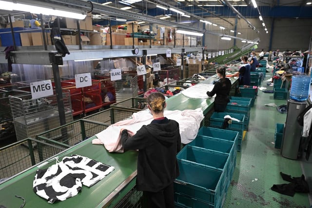 Des employés trient des vêtements reçus au centre de recyclage «Le Relais» à Acigné, dans la banlieue de Rennes, le 21 juillet 2025.
