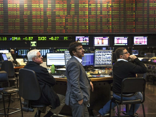 (FILES) In this file photo taken on June 18, 2018, traders look at a screen at the Buenos Aires Stock Exchange. - The Merval index of the Argentine stock market ended a 10-round bullish streak on Wednesday January 18, 2023 with a fall of 9.73% to 235,372.41 points, which analysts attribute to profit-taking after government announcements of a bond repurchase in Dollars. (Photo by EITAN ABRAMOVICH / AFP)