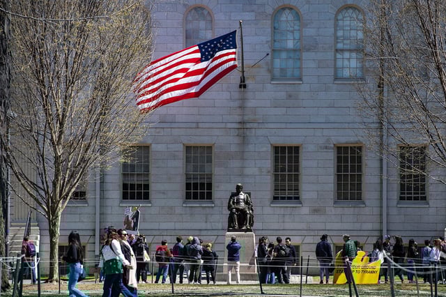 Demonstrators with signs stand around the John Harvard Statue in Harvard Yard after a rally was held against President Donald Trump's attacks on Harvard University at Harvard University in Cambridge, Massachusetts on April 17, 2025.