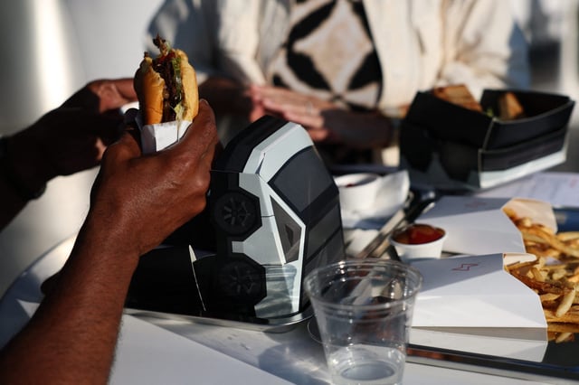 An attendee eats the Tesla burger from a Cybertruck-inspired box during the opening of the Tesla Diner in Los Angeles on July 21. The retro-futuristic restaurant serves up diner classics, including “epic bacon,” tallow-fried french fries, and hot dogs.