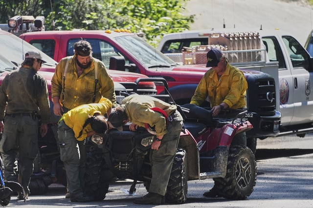 Idaho Department of Lands firefighters inspect an ATV at a staging area near the scene the day after a shooter ambushed and killed multiple firefighters responding to a wildfire at Canfield Mountain Monday, June 30, 2025, in Coeur D'Alene, Idaho. (AP Photo/Lindsey Wasson)