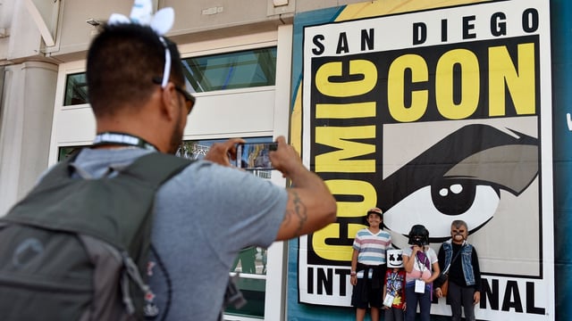 FILE – In this Wednesday, July 18, 2018, file photo, Luis Ramos, left, of San Diego takes a picture of his son Alek, third from right, and daughter Anabel, second from right, and their friends Emiliano Beltran, fourth from right, and Isabel Beltran, before Preview Night at Comic-Con International at the San Diego Convention Center, in San Diego. The four-day 2019 Comic-Con kicks off Wednesday, July 17, 2019, when the showroom floor opens to thousands vying for exclusive merchandise. (Photo by Chris Pizzello/Invision/AP, File)