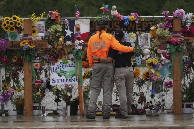 FILE - Members of a search and rescue team embrace as they visit a memorial wall for flood victims, Sunday, July 13, 2025, in Kerrville, Texas. (AP Photo/Eric Gay, File)