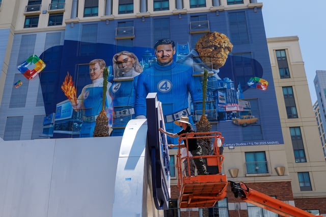 Workers paint and outdoor display next to a hotel wrapped in a Fantastic Four movie advertisement as San Diego prepares to host thousands of visitors for Comic-Con International, in San Diego, California, U.S. July 22, 2025.  REUTERS/Mike Blake/File Photo