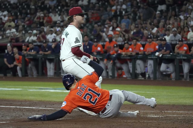 Houston Astros&#39; Yainer Diaz (21) scores a run against the Arizona Diamondbacks pitcher Andrew Saalfrank after a wild pitch in the sixth inning during a baseball game, Wednesday, July 23, 2025, in Phoenix. (AP Photo/Rick Scuteri)