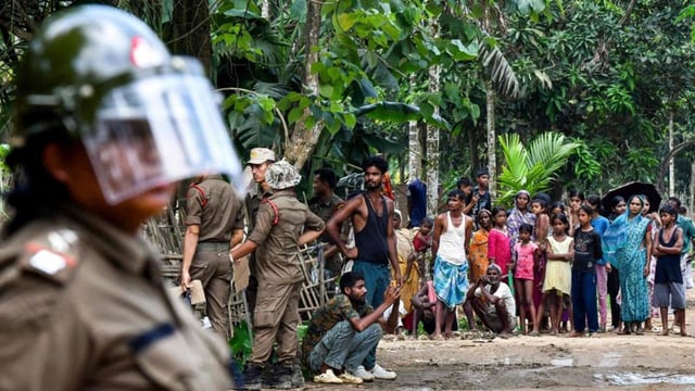 Security personnel stand guard as villagers watch the demolition of their houses by local authorities during an eviction drive at an alleged illegal residential settlement inside the Paikan Reserve Forest in Goalpara district, in Assam (AFP FILE)
