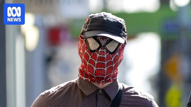 Accused graffiti artist Jack Gibson-Burrell enters court wearing a Spiderman mask, flanked by his lawyer