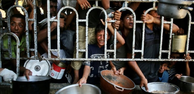 De enfants palestiniens attendent des repas préparés par une organisation de charité locale à al-Mawassi dans le sud de la bande de Gaza, le 22 juilet 2025