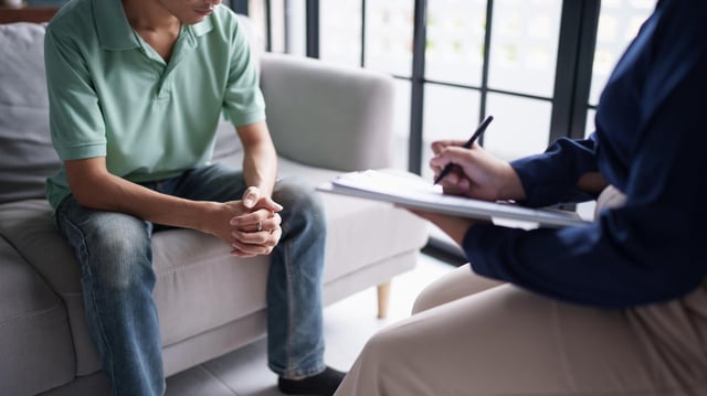 Ein Psychotherapeut macht Notizen bei einer Sitzung mit einem Patienten.