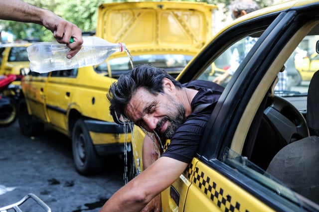 A taxi driver tries to cool off by pouring water on his head on a hot summer day in Tehran, Iran, on July 22, 2025.