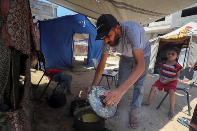 Displaced Palestinian man Nizar Bakron cooks at his tent in Gaza City July 17, 2025. REUTERS/Mahmoud Issa