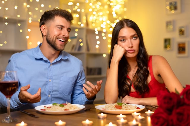 A man gestures to his date as she appears bored.