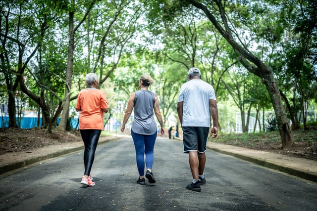 Fitness instructor walking with senior couple at public park