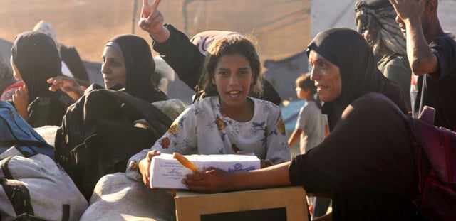 Des femmes et enfants palestiniens après avoir reçu de l'aide humanitaire à un point de distribution de la Fondation humanitaire de Gaza (GHF) à Rafah, le 24 juillet 2025 dans le sud de la bande de Gaza