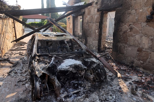 A burnt car is seen, as a wildfire burns in the village of Souni, near Limassol, Cyprus July 24, 2025. REUTERS/Yiannis Kourtoglou