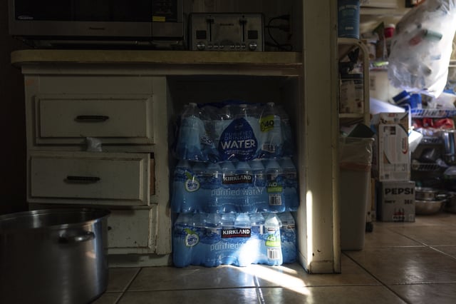 Cases of bottled drinking water are stored under a kitchen counter in the home of Agustin and Ricarda Toledo in Oasis, Calif., Wednesday, Oct. 30, 2024. (AP Photo/Jae C. Hong)