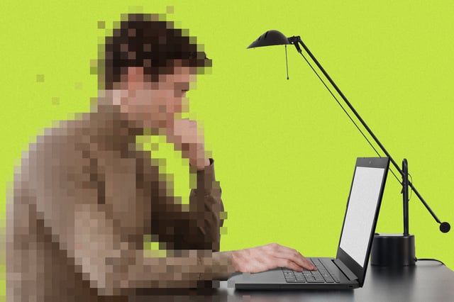 A pixelated person sits at a desk using a laptop with a blank screen, next to a black lamp, against a bright yellow-green background.