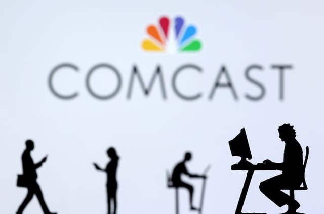 Small toy figures with laptops and smartphones are seen in front of displayed Comcast logo, in this illustration taken December 5, 2021. REUTERS/Dado Ruvic/Illustration/File photo