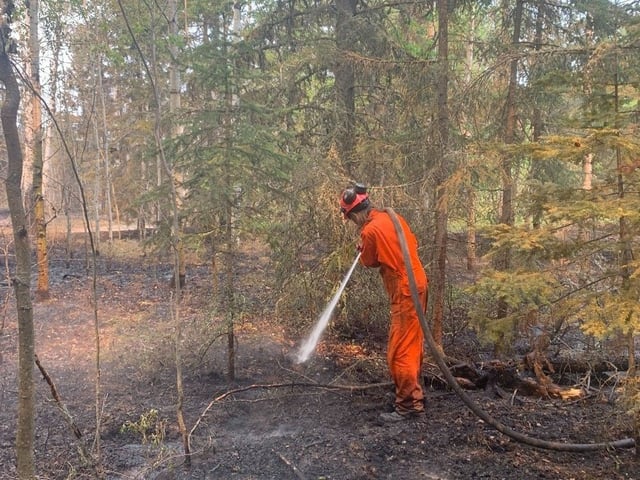 A member of Grant Fire Rescue works to contain a hot spot outside of Creighton, Sask. on June 1, 2025 as the Club wildfire threatens the community.