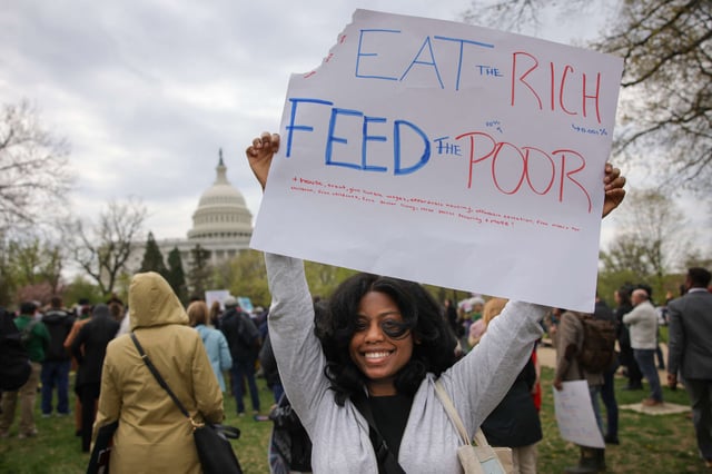 A protester holds a sign reading "eat the rich, feed the poor" during a press conference and rally in support of fair taxation near the U.S. Capitol in Washington, D.C., on April 10, 2025.