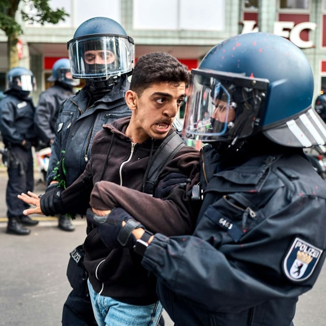 Polizisten führen einen Demonstrationsteilnehmer ab. 