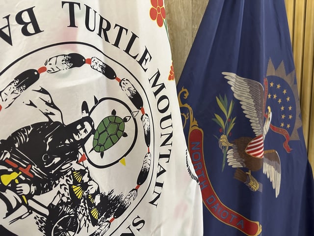 FILE - Flags for the Turtle Mountain Band of Chippewa Indians and the state of North Dakota stand in Memorial Hall of the state Capitol in Bismarck, N.D., on Dec. 15, 2023. (AP Photo/Jack Dura, File)