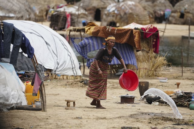 A Fulani woman empties water from a bowl outside her house in Konduga, northeast Nigeria, Wednesday, July 23, 2025. (AP Photo/Sunday Alamba)